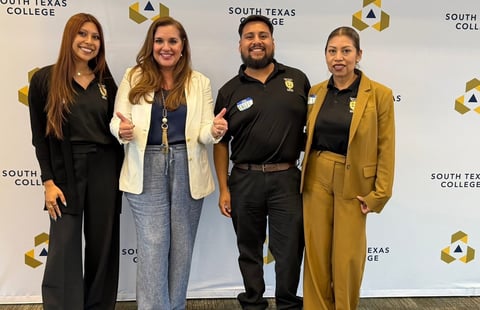 Four people posing together in front of a South Texas College backdrop at an event
