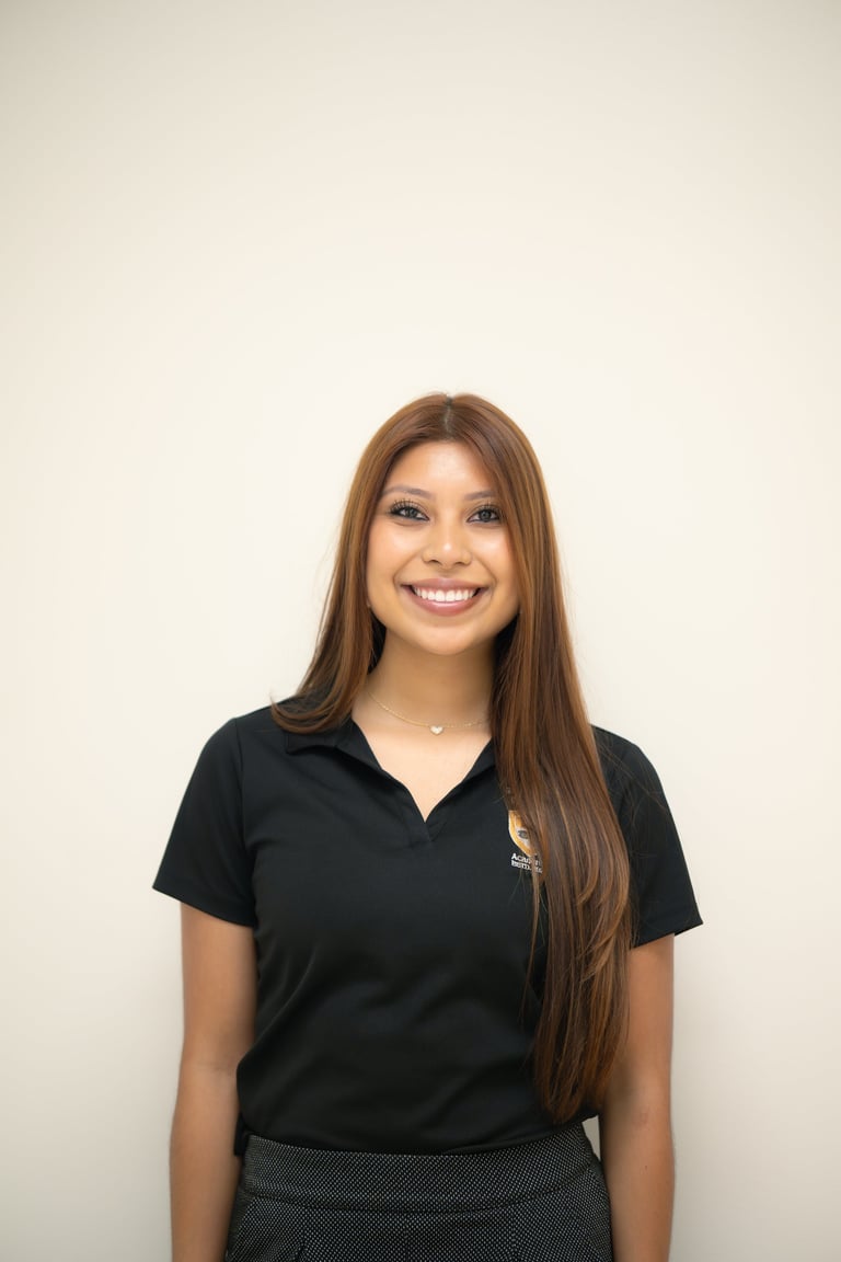 Smiling woman with long brown hair wearing a black polo shirt against a white background